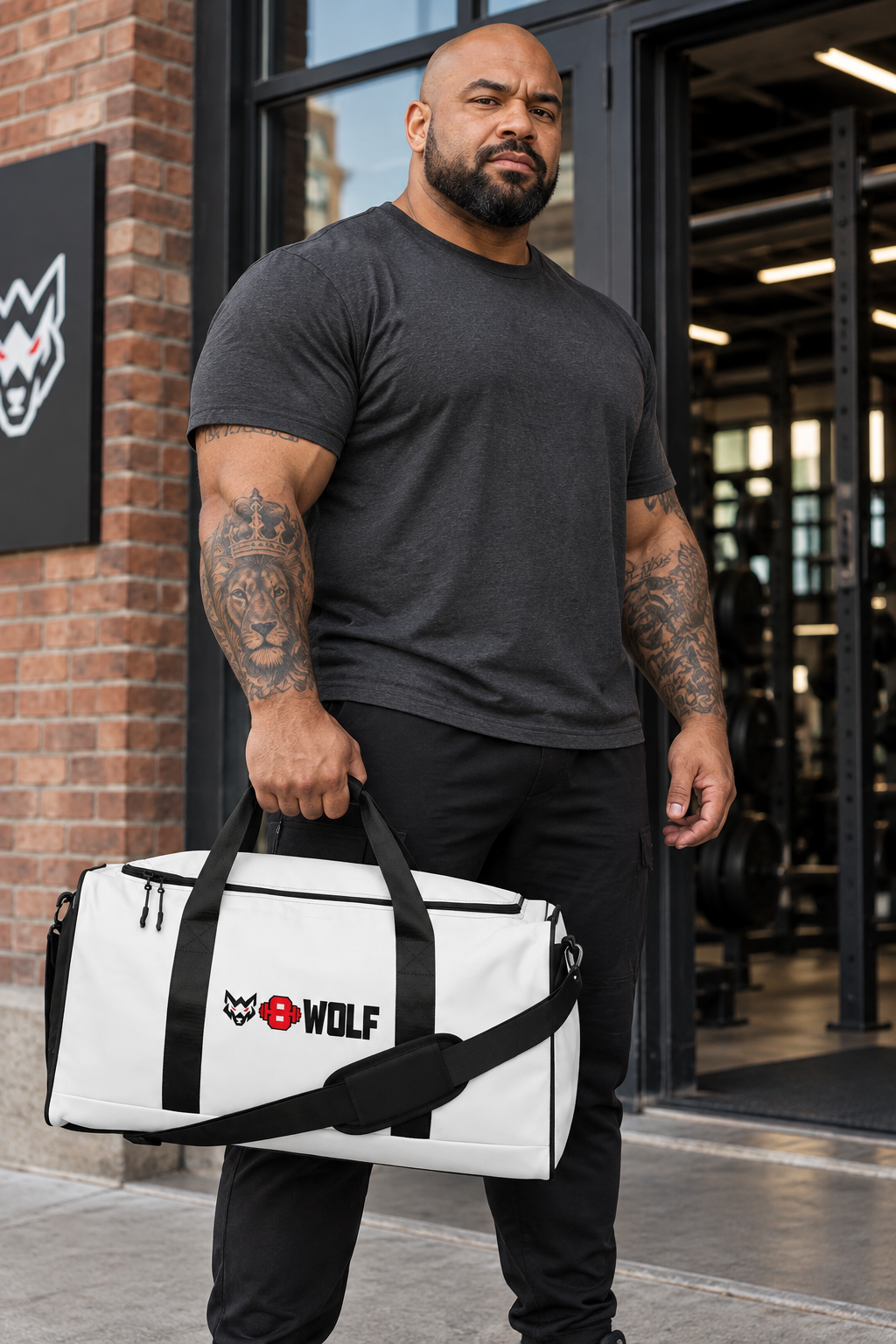 AI-generated original adult tattooed strongman carrying W8WOLF Bold Logo Gym Duffle 50 L in a fictional urban gym setting. Actual white bag black webbing zipper shoulder strap and original black wolf red eyes red barbell8 WOLF front print retained. Clothing styling only; original supplier views retained.