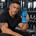 AI-generated original adult tattooed male bodybuilder holding Oxford Blue W8WOLF Flip Straw Training Bottle 25 oz in an urban gym. Actual translucent bottle pivot handle lid and original wolf red barbell8 WOLF print retained. Clothing styling only; other color supplier views retained.