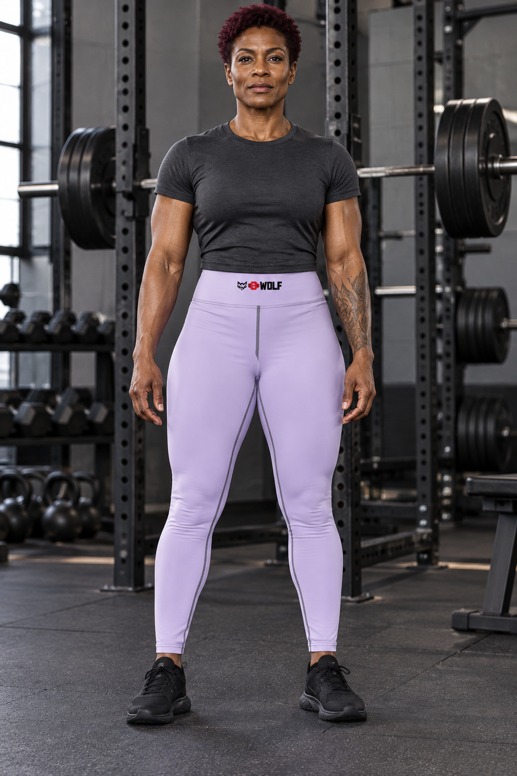 AI-generated original adult tattooed female powerlifter wearing W8WOLF Womens Yoga Leggings Lavender in an urban gym. Actual pale lavender high waist plain front dark seams and small original wolf red barbell8 WOLF waistband mark retained. Tee and shoes styling only.