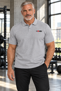 AI-generated original adult male strength athlete wearing Sport Grey W8WOLF Essentials Pique Polo in an urban strength gym. Actual two-button construction and small black wolf red barbell8 WOLF left chest mark retained. Black trousers styling only; White variant supplier photos retained.