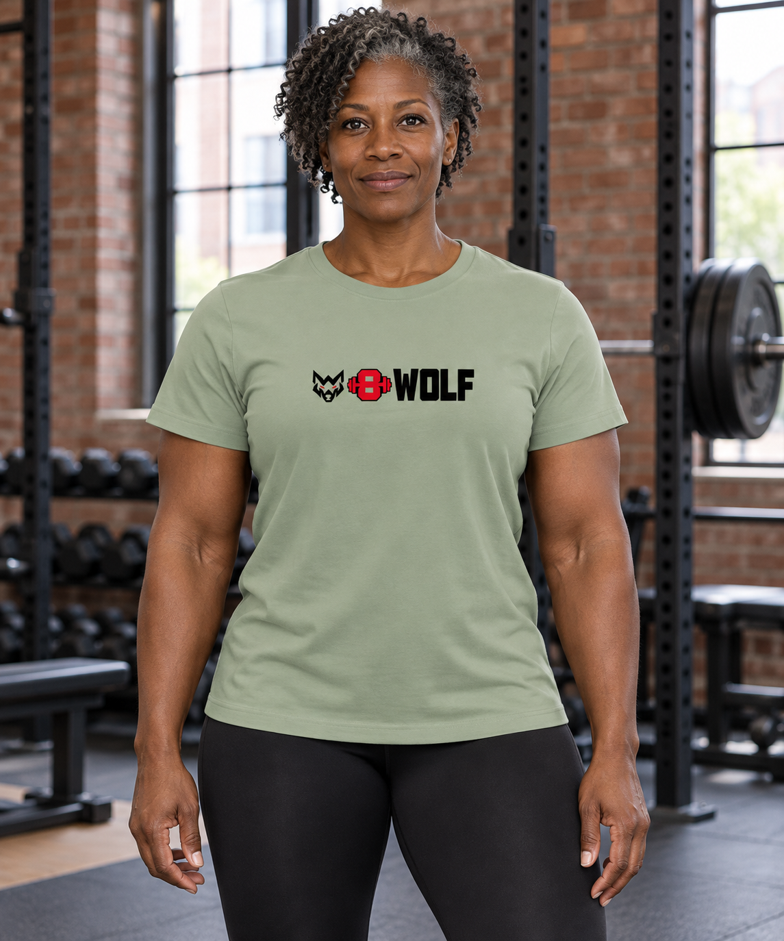 AI-generated original adult female powerlifter wearing Sage W8WOLF Essentials Womens Relaxed Tee in an urban gym. Actual sage relaxed cut and original black wolf red eyes red barbell8 WOLF chest artwork retained. Leggings styling only; other color photos retained.