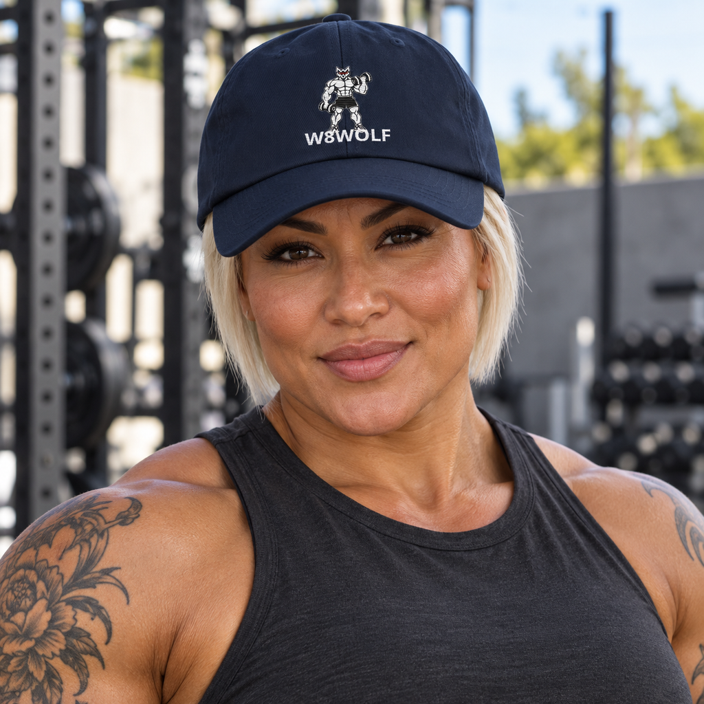 AI-generated original adult tattooed female bodybuilder wearing W8WOLF Iron Curl Signature Dad Hat Navy at an urban outdoor gym. Actual navy curved brim white embroidered lifting wolf red eyes and W8WOLF below retained. Tee styling only.