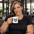 AI-generated original adult female bodybuilder holding W8WOLF Wolf Emblem Mug 11 oz in an urban gym lounge. Actual white ceramic mug and original black wolf red eyes front artwork retained. Clothing styling only; original supplier image retained.